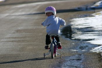 小女孩骑着带辅助轮的自行车